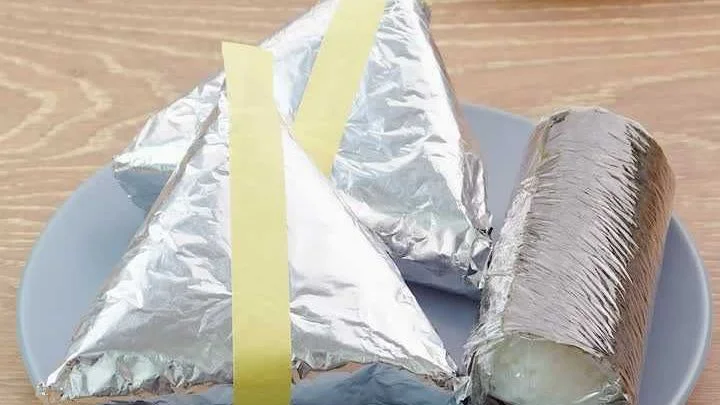 Onigiri wrapped in foil, each with a strip of tape for tearing it open